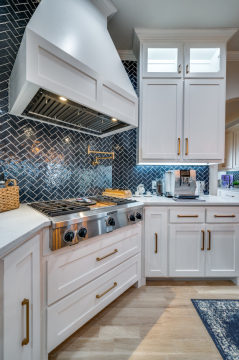 stove top with blue backsplash and white cabinets with gold hardware